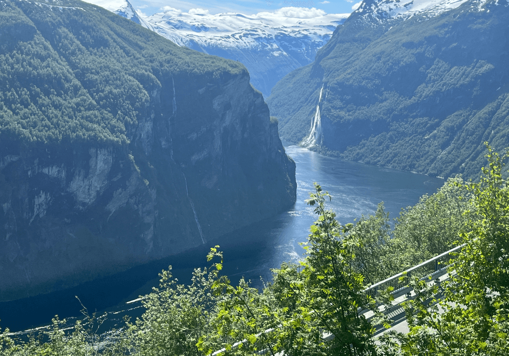 A deep fjord winding between steep green mountains and waterfalls.